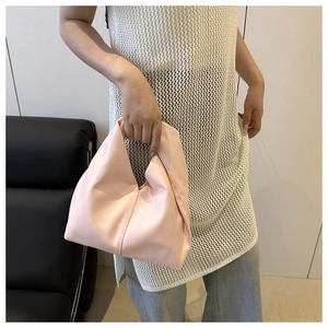 Close-up of light pink leather cloud bag with soft pleats and knotted handle detail