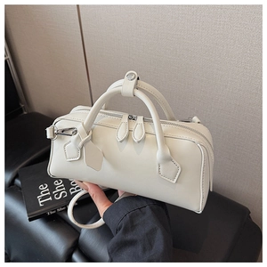 Detail of white Boston handbag with dual zippers, round handles, and detachable strap