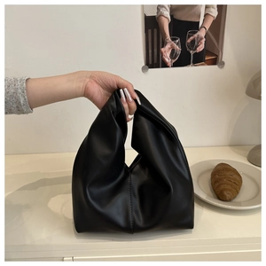 Detailed view of black dumpling bag featuring a knotted handle and soft pleated PU leather