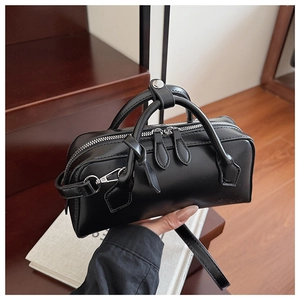 Detail of a black Boston handbag featuring dual silver zippers and glossy leather texture