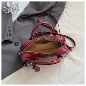 Macro view of burgundy handbag interior showing light brown lining and zip pocket