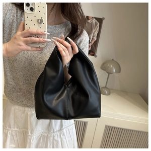 Close-up of black pleated dumpling cloud handbag with soft leather texture and handle