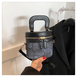 Detail der Eimertasche aus schwarzem Leder und blauem Denim mit goldenem Reißverschluss