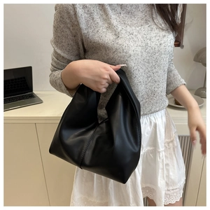 Close-up of a black pleated dumpling bag held on a model's arm for stylish wear