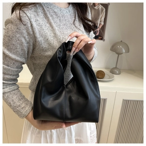 Close-up of black pleated PU leather dumpling bag with unique knotted handle design