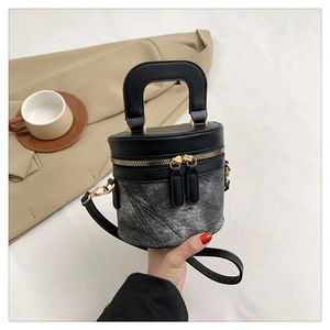Detail der Vintage-Jeans und schwarzen Leder-Eimertasche mit goldenen Beschlägen