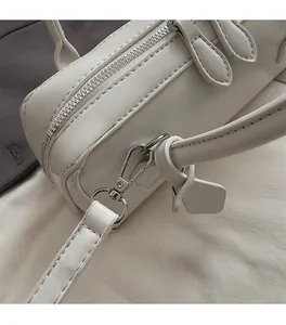 Close-up of polished silver hardware and leather texture on a beige crossbody handbag