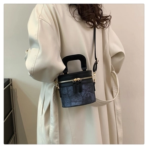 Detail einer blauen Bucket Bag mit Denim-Struktur, Ledergriff und goldenem Reißverschluss