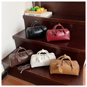 Detail view of five colors of minimalist Boston handbags with detachable straps on wooden steps