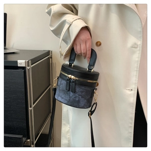 Detail einer schwarzen Beuteltasche mit grauer Textur und goldener Hardware am Modell