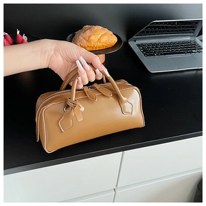 Close-up of a vintage brown leather Boston handbag with sturdy double handles