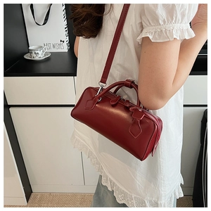 Detail of a burgundy glossy leather mini Boston bag with silver hardware and top handles
