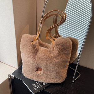 Braune Plüsch-Tragetasche mit Lederriemen auf Holztisch in warmer Winteratmosphäre