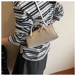 Detail view of a minimalist cream Boston bag with sleek handles and adjustable shoulder strap
