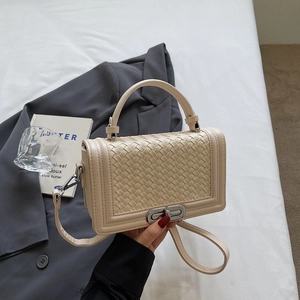 Quilted cream shoulder bag with woven texture and silver metal twist lock closure