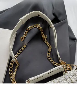 Detail of white tweed shoulder bag featuring gold chain strap and fine weaving texture