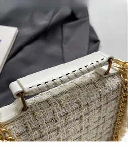 Detail of tweed fabric texture with woven handle and gold chain on the shoulder bag