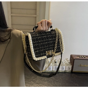 Close-up of tweed handbag with pearl trim, gold hardware, and metal chain strap details