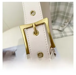 Detailed view of adjustable cream leather shoulder strap with gold metal buckle