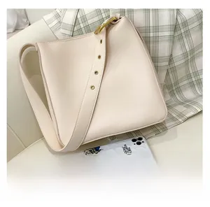 Detail of cream leather shoulder bag showing wide strap with retro gold eyelets