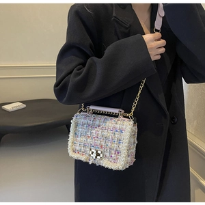 Close-up of colorful tweed handbag with pearl trim and gold chain strap worn by model