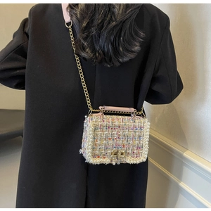 Detail of tweed crossbody bag with pearl trim and gold chain on model in black coat