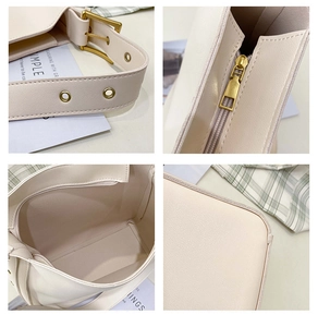 Detail view of off-white bucket bag showing adjustable strap and golden metal buckle