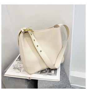 Detail of cream leather shoulder bag with wide strap and golden metal hardware