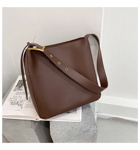 Detail of minimalist dark brown leather bucket bag with gold clasp on stone background