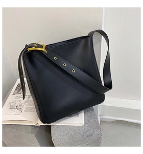 Detail of adjustable strap with gold eyelets on a black matte leather bucket bag