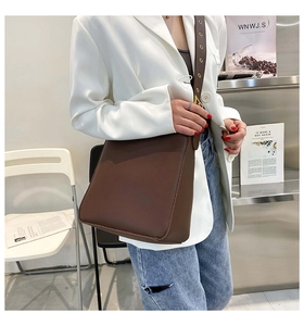 Detail of a large brown leather bucket bag worn with white blazer and jeans