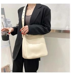 Detail view of cream beige tote bag featuring a wide shoulder strap with gold metal eyelets