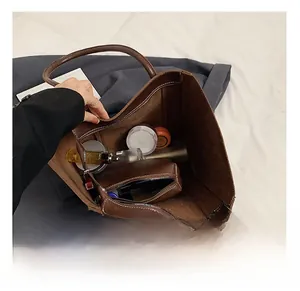 Top view of spacious brown leather tote bag interior showing various items for daily use