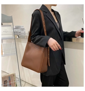 Deep brown minimalist tote bag shown from side profile with adjustable shoulder strap