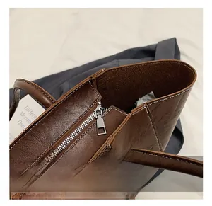 Detail of high-quality metal zipper closure on deep brown leather tote bag