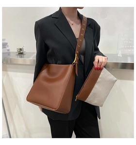 Detail of a brown leather bucket bag and pouch set worn by a model in a modern suit