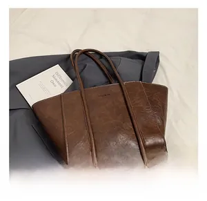 Detail view of large brown leather tote bag with FASHION logo and white contrast stitching