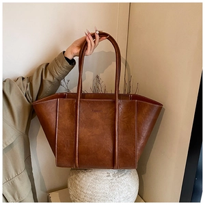 Detail of vintage brown tote bag with contrast stitching and embossed fashion logo