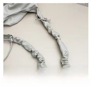 Close-up of ruched leather shoulder strap and silver metal zipper on a beige bag