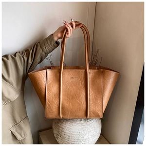 Detail of light brown tote bag featuring crinkled leather texture and fashion embossing