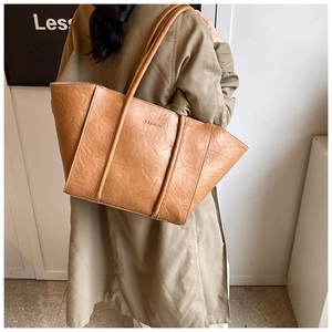 Detail of tan tote bag with unique crinkled leather texture and embossed FASHION text