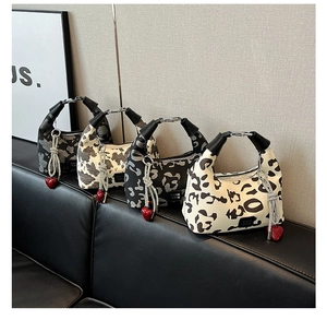 Detail of half-moon handbags in animal prints with red heart charms and woven tassels