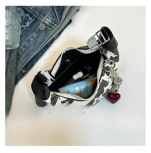 Detail view of cow print baguette bag interior showing capacity for cosmetics and heart charm