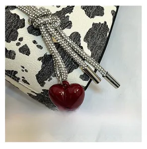 Macro shot of cow print bag featuring rhinestone knot and red heart charm detail