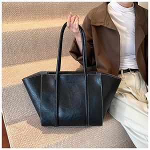Detail of vintage black leather tote bag with white contrast stitching and long straps