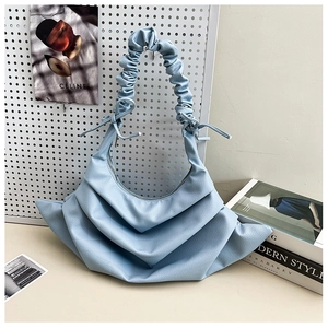 Detail of light blue pleated shoulder bag with textured leather and bow drawstring accents