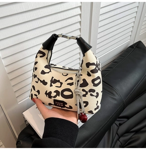 Detail of leopard print hobo bag featuring cherry charm and silver rhinestone lanyard