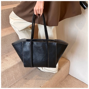 Black tote bag detail featuring white contrast stitching and embossed fashion logo