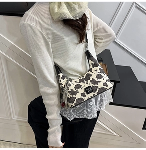 Detail view of cow print shoulder bag with black strap and silver tassel chain