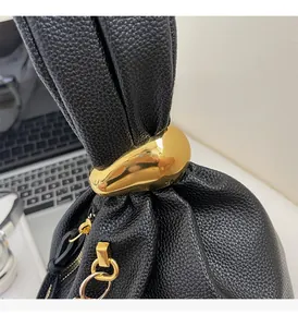 Detail of premium gold-toned teardrop hardware and lychee grain leather on a black handbag